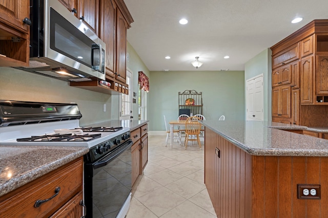 13506 Scenic Glade Dr, Houston, TX 77059 - kitchen featuring gas stove, stainless steel microwave, dark stone counters, recessed lighting, and brown cabinetry