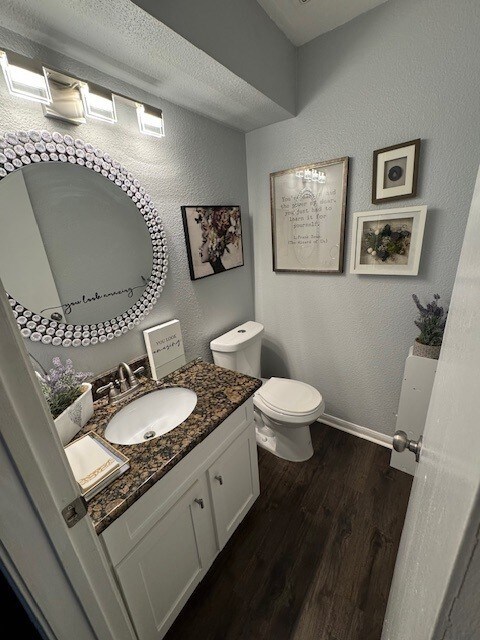 2211 S Kirkwood Rd Unit 1, Houston, TX 77077 - half bath with toilet, wood finished floors, vanity, a textured wall, and baseboards