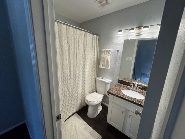 2211 S Kirkwood Rd Unit 1, Houston, TX 77077 - bathroom featuring wood finished floors, vanity, toilet, a textured wall, and curtained shower