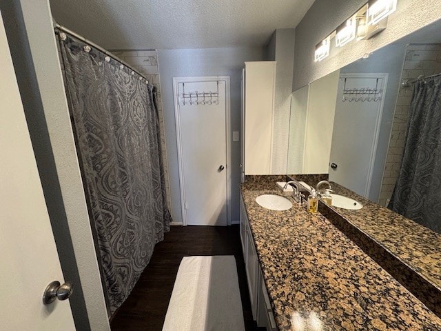 2211 S Kirkwood Rd Unit 1, Houston, TX 77077 - bathroom with wood finished floors, a textured ceiling, and double vanity