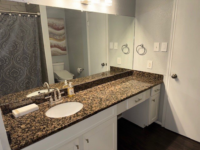 2211 S Kirkwood Rd Unit 1, Houston, TX 77077 - full bath with toilet, wood finished floors, vanity, a shower with shower curtain, and a textured wall