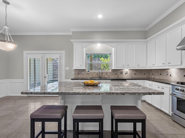 13 Hickory Shadows Dr, Houston, TX 77055 - kitchen with stainless steel stove, a sink, white cabinets, crown molding, and wainscoting