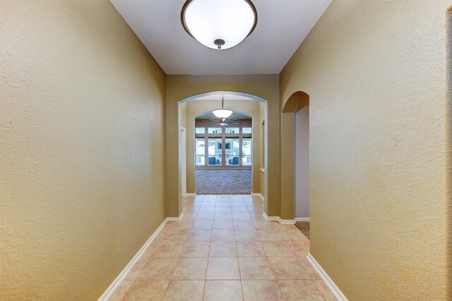 1810 Spreading Bough Ln, Richmond, TX 77406 - hallway with arched walkways, light tile patterned floors, a textured wall, and baseboards