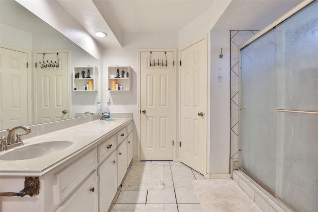 bathroom featuring a stall shower, double vanity, and tile patterned floors