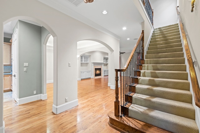 6230 Elm Heights Ln, Houston, TX 77081 - staircase featuring crown molding, wood finished floors, recessed lighting, a fireplace with flush hearth, and baseboards