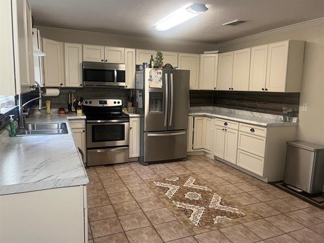 13375 Craig Ln, Bevil Oaks, TX 77713 - kitchen featuring appliances with stainless steel finishes, a sink, tasteful backsplash, light countertops, and ornamental molding