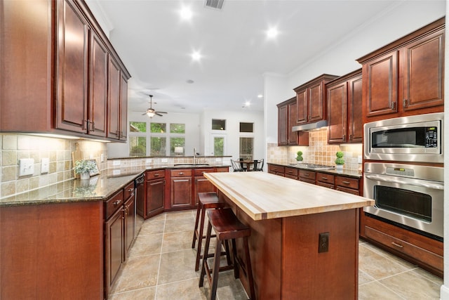 27259 Jessica Hills Ln, Spring, TX 77386 - kitchen featuring appliances with stainless steel finishes, butcher block countertops, a peninsula, backsplash, and a sink