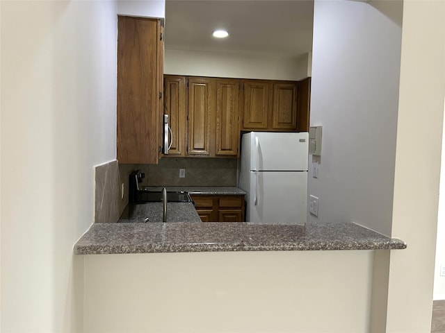 2213 S Braeswood Blvd Unit 12B, Houston, TX 77030 - kitchen with freestanding refrigerator, a peninsula, stainless steel microwave, backsplash, and stove
