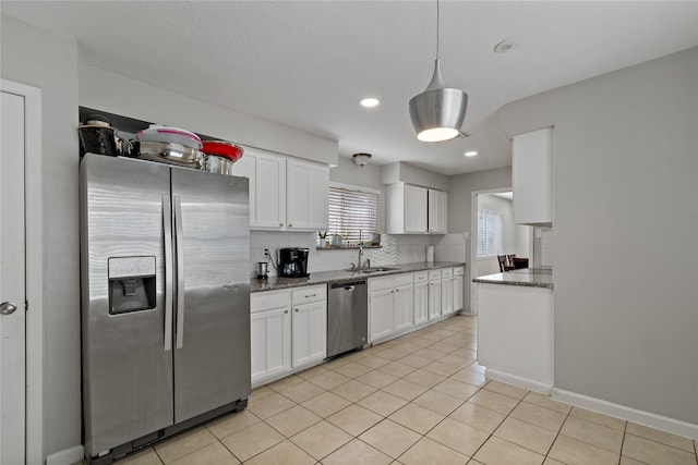 19411 Southaven Dr, Houston, TX 77084 - kitchen featuring appliances with stainless steel finishes, white cabinetry, light tile patterned floors, a sink, and dark stone counters