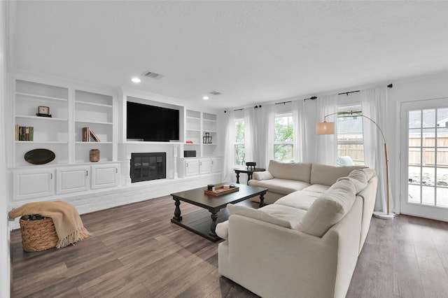 16419 Fox Crossing Ln, Spring, TX 77379 - living area featuring plenty of natural light, wood finished floors, a glass covered fireplace, recessed lighting, and a textured ceiling