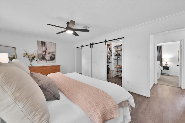 16419 Fox Crossing Ln, Spring, TX 77379 - bedroom with a barn door, wood finished floors, a spacious closet, crown molding, and a ceiling fan