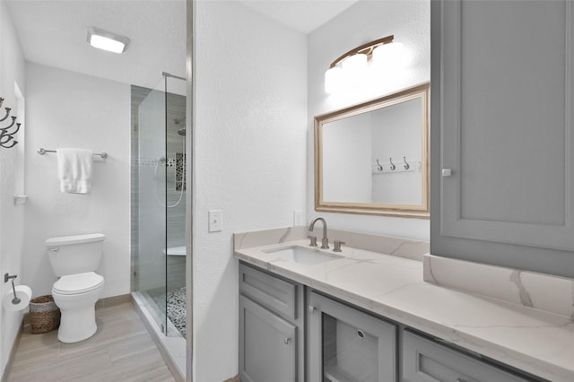 16419 Fox Crossing Ln, Spring, TX 77379 - full bathroom featuring a shower stall, toilet, vanity, wood finished floors, and a textured wall