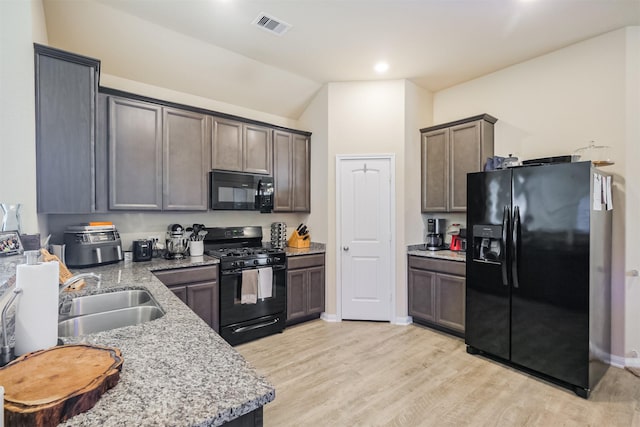14657 E Pine Heart Dr, Conroe, TX 77302 - kitchen with black appliances, a sink, light stone counters, light wood-style floors, and lofted ceiling