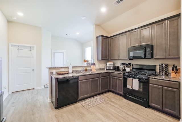 14657 E Pine Heart Dr, Conroe, TX 77302 - kitchen featuring black appliances, vaulted ceiling, a sink, light stone counters, and light wood-type flooring
