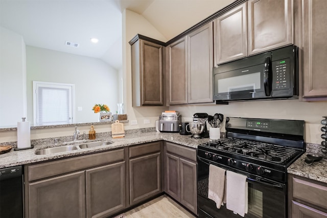 14657 E Pine Heart Dr, Conroe, TX 77302 - kitchen with black appliances, vaulted ceiling, a sink, light stone countertops, and light wood-style floors