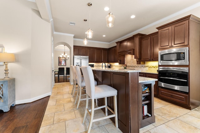 2322 Dolan Springs Ln, Friendswood, TX 77546 - kitchen with appliances with stainless steel finishes, ornamental molding, decorative backsplash, light stone countertops, and hanging light fixtures