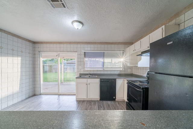 751 Terryhollow St, Channelview, TX 77530 - kitchen with black appliances, white cabinets, under cabinet range hood, wood finished floors, and tile walls