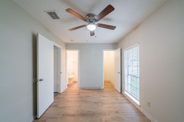 751 Terryhollow St, Channelview, TX 77530 - unfurnished bedroom with light wood-style floors, baseboards, a textured ceiling, connected bathroom, and a ceiling fan