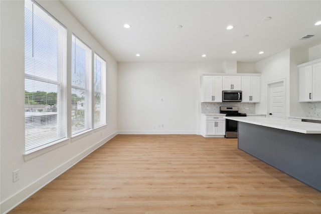 4629 Balkin St, Houston, TX 77021 - kitchen with stainless steel appliances, backsplash, recessed lighting, white cabinets, and light wood-style flooring