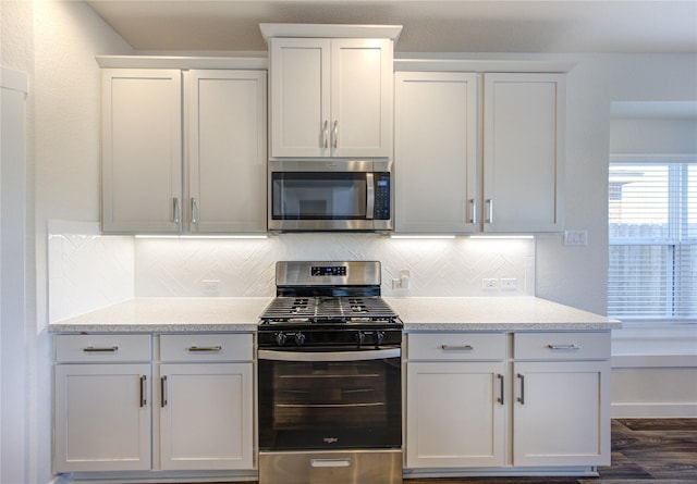 3033 Myrtle Sunset Dr, Katy, TX 77493 - kitchen featuring appliances with stainless steel finishes, backsplash, dark wood-type flooring, white cabinets, and light stone counters