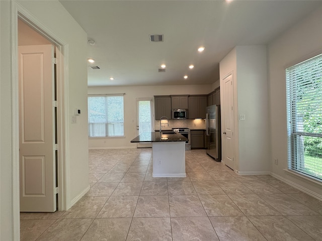 130 Moon Dance Ct, Conroe, TX 77304 - kitchen with stainless steel appliances, plenty of natural light, light tile patterned floors, backsplash, and recessed lighting