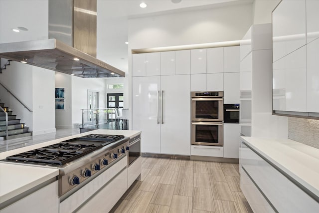 5430 Judalon Ln, Houston, TX 77056 - kitchen featuring island range hood, modern cabinets, appliances with stainless steel finishes, white cabinets, and light countertops