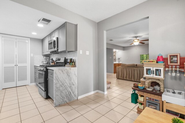3623 Wells Mark Dr, Humble, TX 77396 - kitchen with appliances with stainless steel finishes, gray cabinets, light countertops, light tile patterned floors, and decorative backsplash