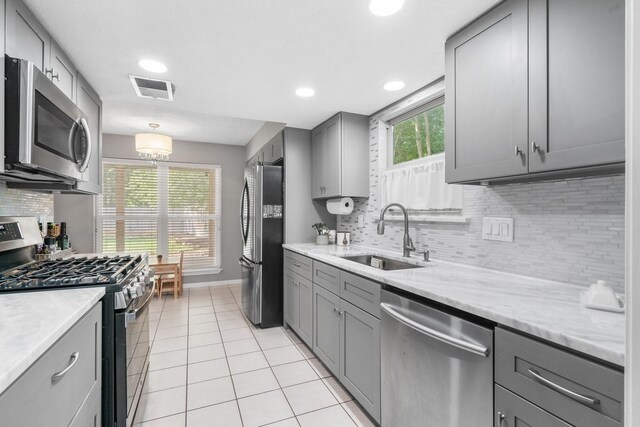 3623 Wells Mark Dr, Humble, TX 77396 - kitchen featuring appliances with stainless steel finishes, gray cabinets, tasteful backsplash, light tile patterned floors, and recessed lighting