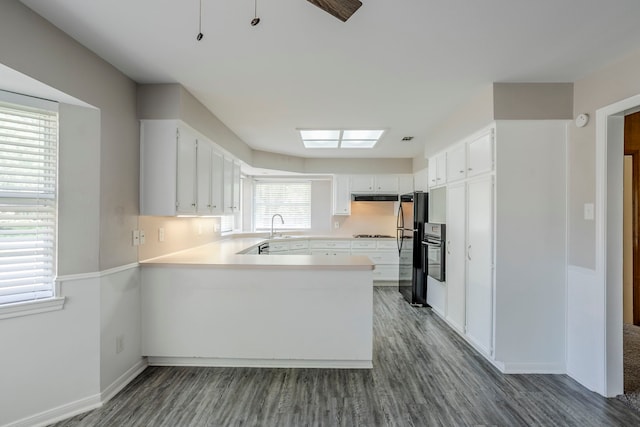 8015 Durklyn Ln, Houston, TX 77070 - kitchen featuring a sink, a peninsula, dark wood finished floors, light countertops, and white cabinetry