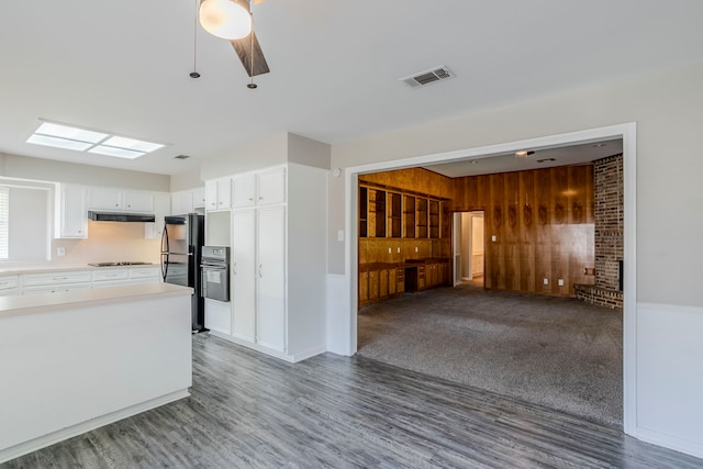 8015 Durklyn Ln, Houston, TX 77070 - kitchen with under cabinet range hood, black appliances, wood finished floors, and white cabinets