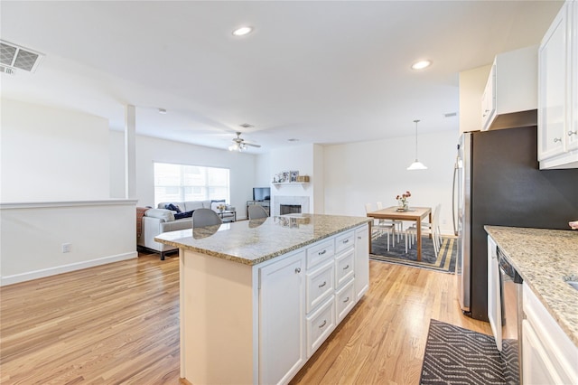 11509 Main Ash, Houston, TX 77025 - kitchen featuring a ceiling fan, light wood-style floors, a fireplace, white cabinets, and a center island