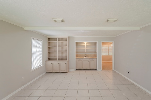 7803 Hurst Forest Dr, Humble, TX 77346 - empty room featuring a textured ceiling, healthy amount of natural light, a sink, baseboards, and ornamental molding