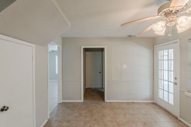 7803 Hurst Forest Dr, Humble, TX 77346 - unfurnished room with a textured ceiling, light tile patterned floors, a ceiling fan, baseboards, and a wainscoted wall