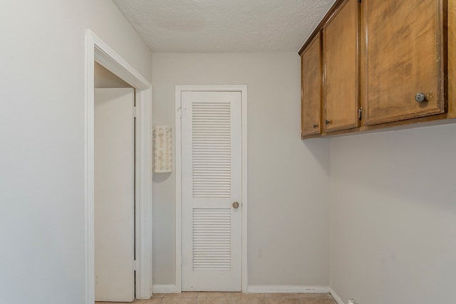 7803 Hurst Forest Dr, Humble, TX 77346 - washroom with a textured ceiling, baseboards, and light tile patterned floors