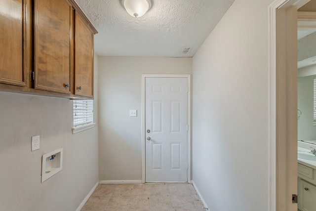 7803 Hurst Forest Dr, Humble, TX 77346 - washroom featuring washer hookup, baseboards, cabinet space, and a textured ceiling