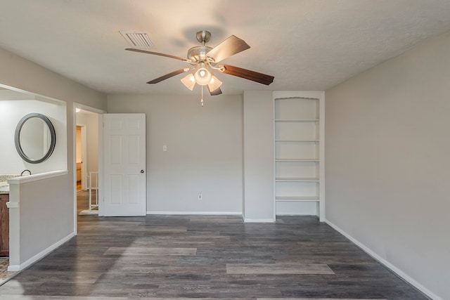 7803 Hurst Forest Dr, Humble, TX 77346 - empty room with ceiling fan, dark wood-style floors, built in shelves, and baseboards