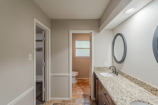 7803 Hurst Forest Dr, Humble, TX 77346 - bathroom featuring toilet, double vanity, a walk in closet, and stone tile flooring