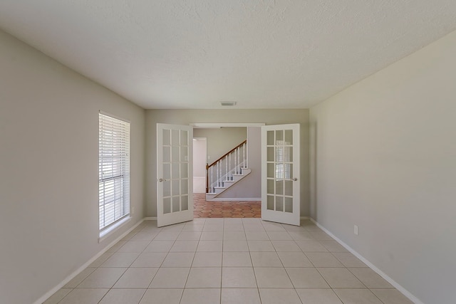 7803 Hurst Forest Dr, Humble, TX 77346 - unfurnished room with french doors, healthy amount of natural light, baseboards, and a textured ceiling