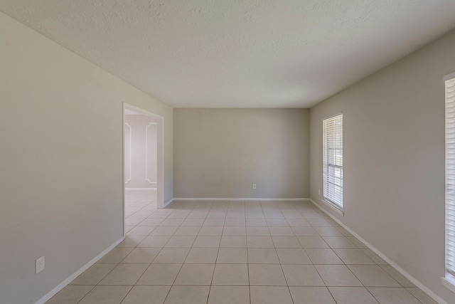 7803 Hurst Forest Dr, Humble, TX 77346 - empty room featuring a textured ceiling, light tile patterned floors, and baseboards