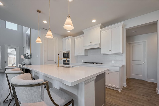 11430 Bush Clover Dr, Cypress, TX 77433 - kitchen with a sink, tasteful backsplash, white cabinets, dark wood-style flooring, and a kitchen island with sink