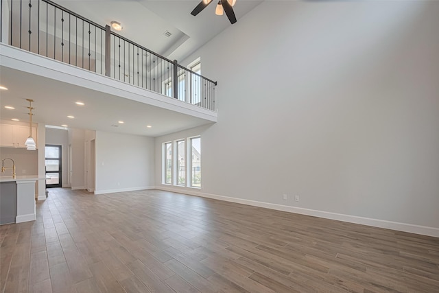 11430 Bush Clover Dr, Cypress, TX 77433 - unfurnished living room with ceiling fan, wood finished floors, baseboards, recessed lighting, and a high ceiling