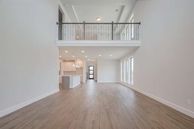 11430 Bush Clover Dr, Cypress, TX 77433 - unfurnished living room with a towering ceiling, light wood-style floors, baseboards, a sink, and recessed lighting