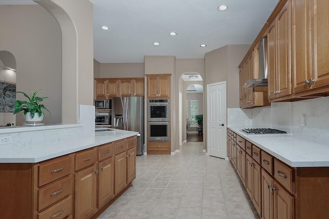 87 S Bluff Creek Cir, The Woodlands, TX 77382 - kitchen featuring arched walkways, stainless steel appliances, wall chimney exhaust hood, backsplash, and recessed lighting