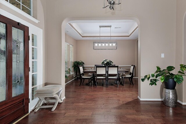 87 S Bluff Creek Cir, The Woodlands, TX 77382 - dining space with arched walkways, a tray ceiling, dark wood-style floors, and baseboards