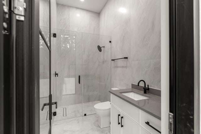 full bathroom featuring tile walls, marble finish flooring, a marble finish shower, vanity, and toilet