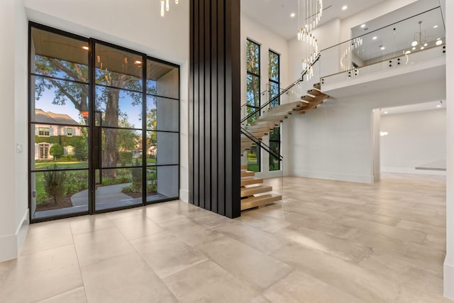 tiled foyer with a high ceiling, stairs, and baseboards
