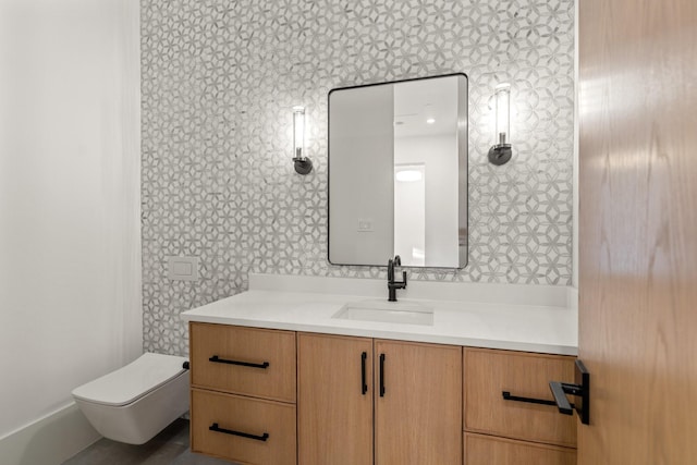 bathroom with wallpapered walls, toilet, and vanity