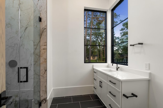 bathroom featuring a marble finish shower, tile patterned floors, vanity, and baseboards