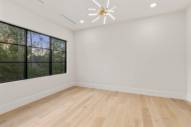 spare room with a chandelier, baseboards, recessed lighting, and light wood finished floors