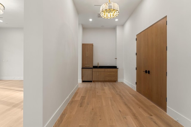 hallway featuring light wood-style floors, a chandelier, recessed lighting, and baseboards